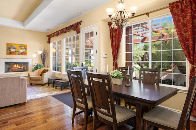 dining space with a notable chandelier, hardwood / wood-style flooring, and a fireplace