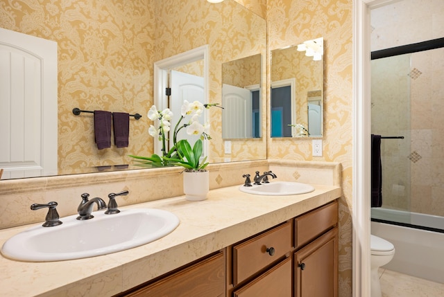 bathroom featuring a sink, wallpapered walls, toilet, and double vanity