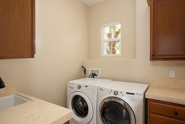 clothes washing area featuring a sink, cabinet space, and washer and dryer