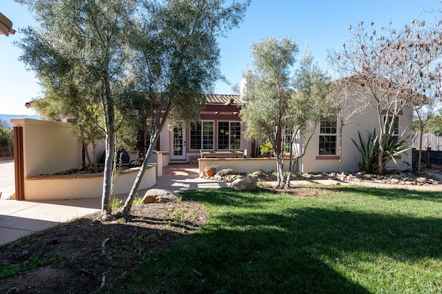 back of property featuring a yard and stucco siding