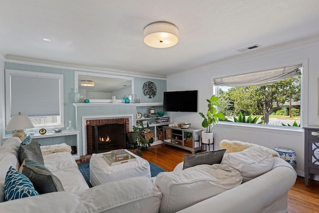 living area featuring visible vents, ornamental molding, wood finished floors, and a fireplace