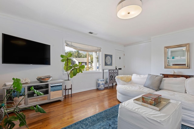 living room featuring visible vents, baseboards, crown molding, and hardwood / wood-style floors
