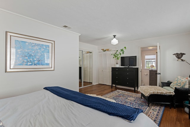 bedroom with crown molding, wood finished floors, and visible vents