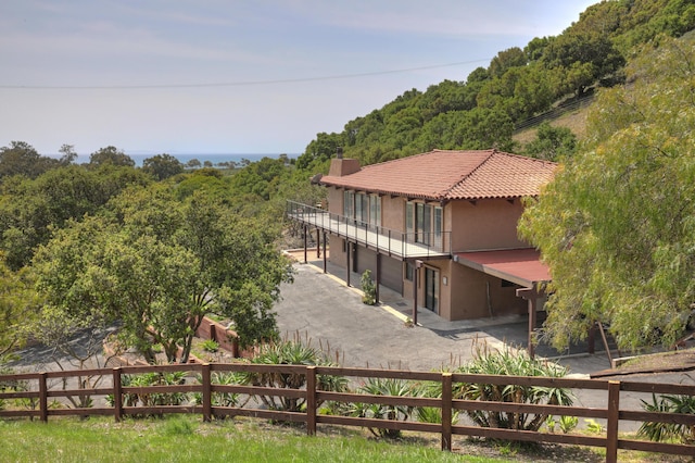 35 Hollister Ranch Rd, Goleta, CA 93117 - back of property featuring driveway, a balcony, stucco siding, a tile roof, and a view of trees