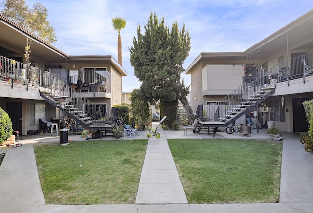 view of property's community with a yard, a patio area, and stairway