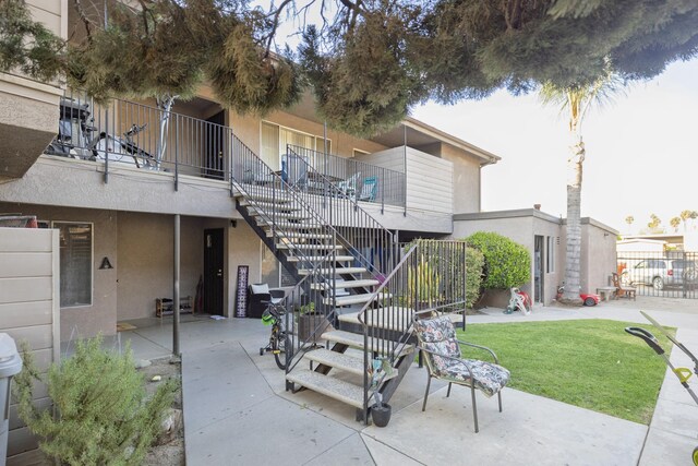view of home's community with a lawn, stairs, and a patio