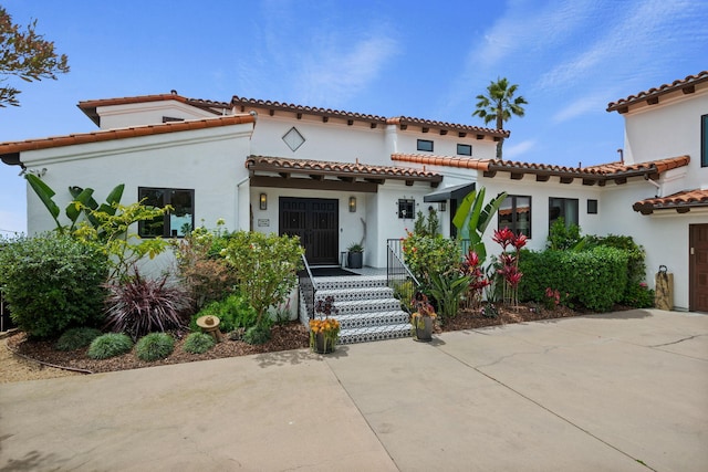 mediterranean / spanish house featuring a tile roof and stucco siding