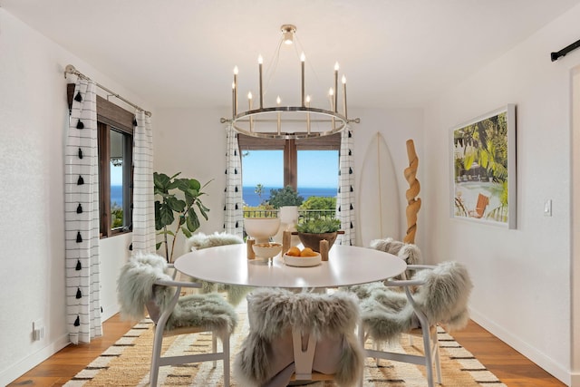 dining room featuring baseboards, light wood-style flooring, and a notable chandelier
