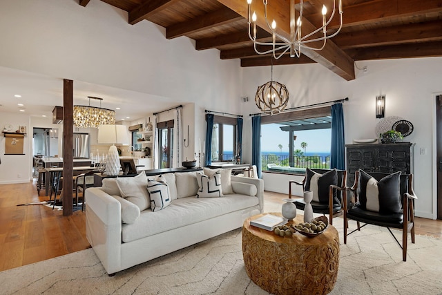 living room with light wood finished floors, beam ceiling, and a notable chandelier