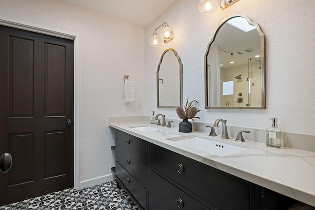 bathroom featuring double vanity, a sink, baseboards, and tile patterned flooring