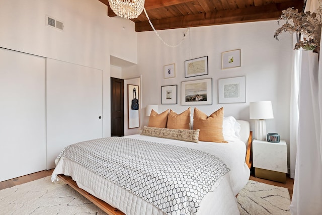 bedroom featuring a notable chandelier, wood finished floors, beamed ceiling, visible vents, and wood ceiling