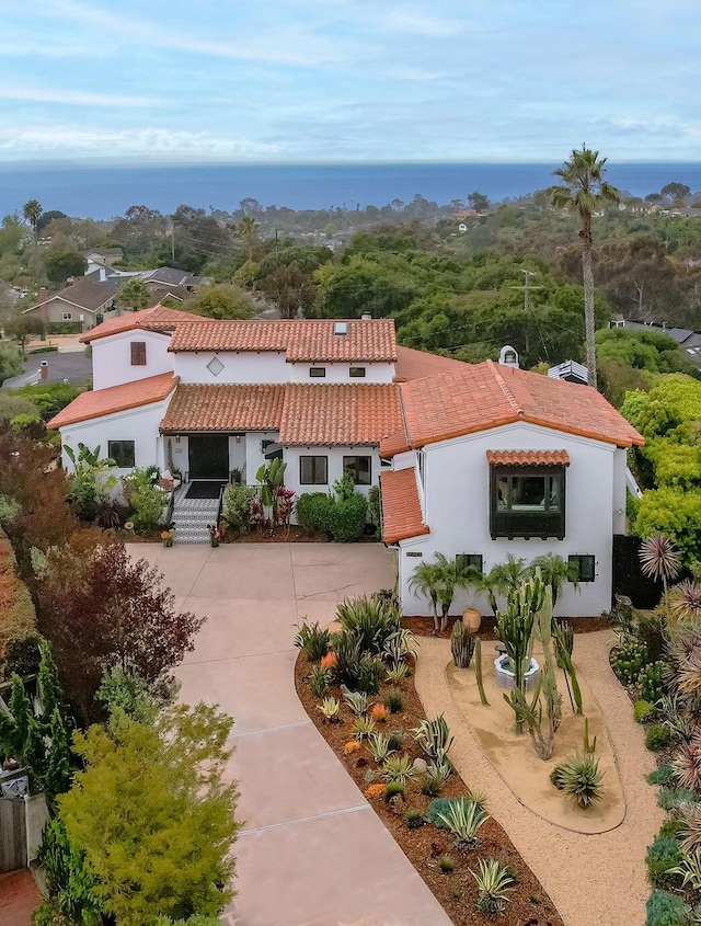view of front of house with a water view, curved driveway, a tile roof, and stucco siding