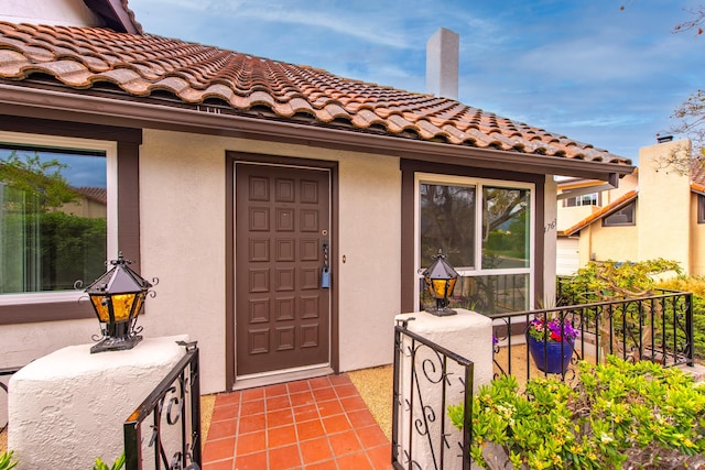 doorway to property with a tiled roof and stucco siding