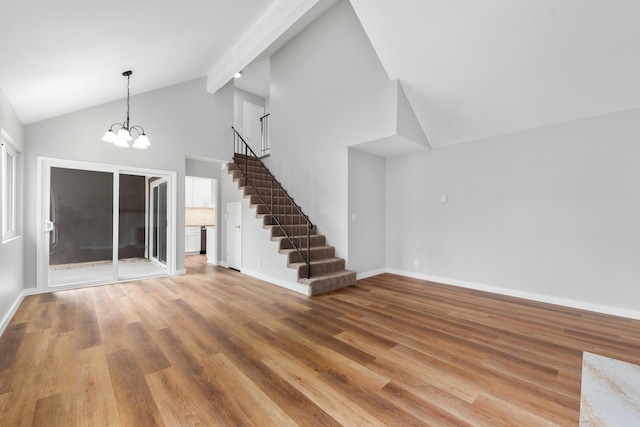 unfurnished living room featuring baseboards, high vaulted ceiling, wood finished floors, and stairway