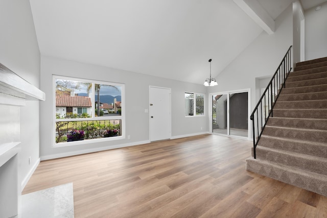 foyer entrance with an inviting chandelier, a healthy amount of sunlight, beam ceiling, and stairway