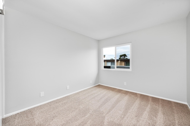 spare room featuring carpet floors and baseboards