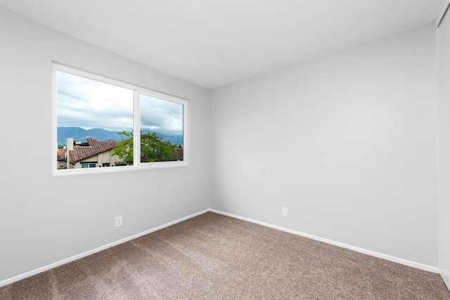 spare room with carpet floors, baseboards, and a mountain view