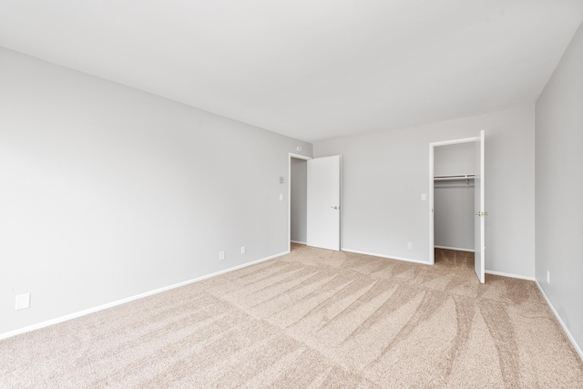 unfurnished bedroom featuring baseboards, carpet, a walk in closet, and a closet