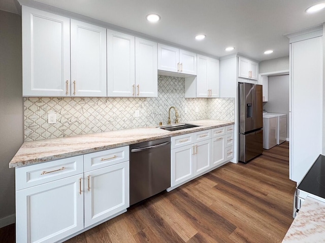 kitchen featuring dark wood-style flooring, appliances with stainless steel finishes, a sink, white cabinets, and washer and clothes dryer