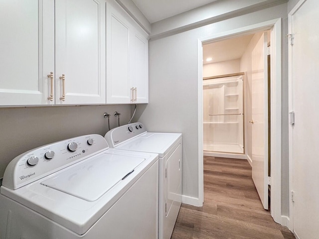 washroom with baseboards, cabinet space, wood finished floors, and washing machine and clothes dryer