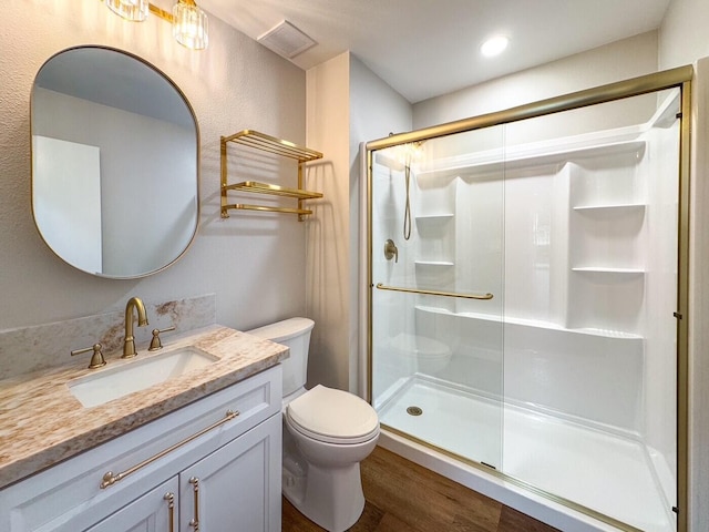 full bathroom featuring visible vents, vanity, wood finished floors, toilet, and a shower stall