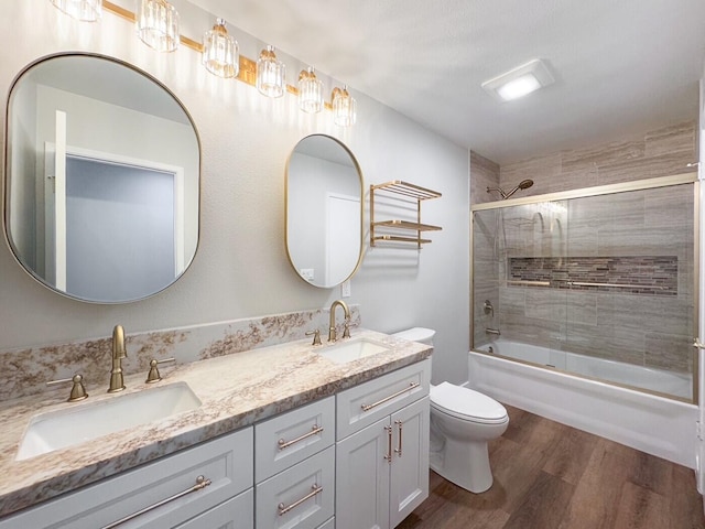 full bath with double vanity, toilet, a sink, and wood finished floors
