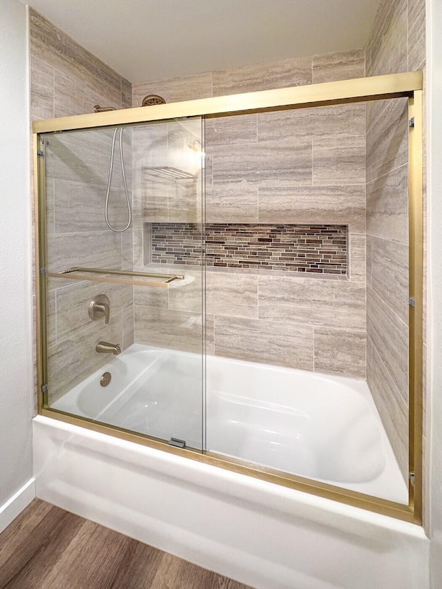 bathroom featuring baseboards, enclosed tub / shower combo, and wood finished floors