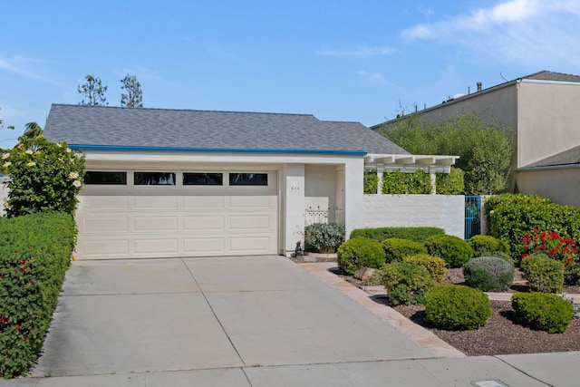 view of front facade with a shingled roof, fence, an attached garage, and concrete driveway