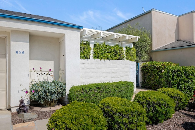 view of side of home with a pergola and stucco siding