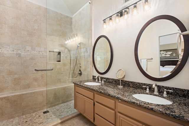 full bathroom with a sink, ensuite bathroom, a tile shower, and double vanity