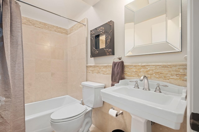 bathroom with a sink, toilet, shower / bath combination with curtain, a wainscoted wall, and tile walls
