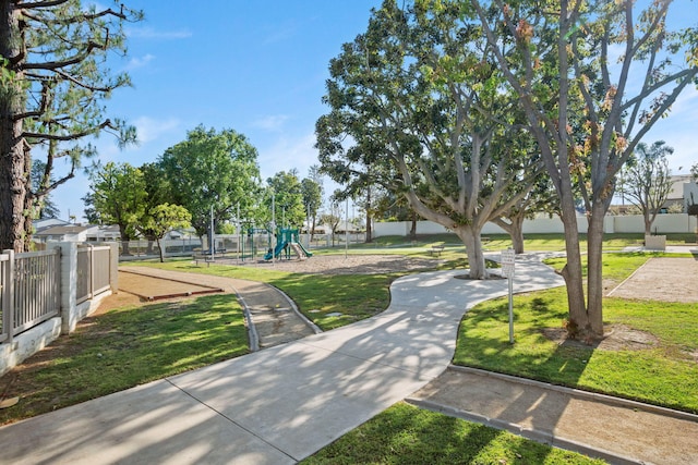 surrounding community with a lawn, fence, and playground community