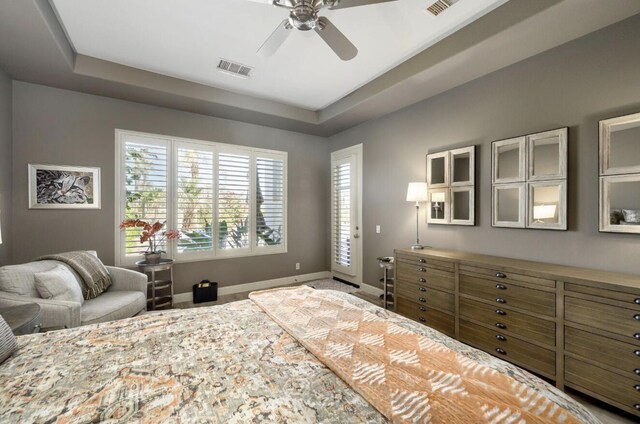 bedroom with baseboards, a ceiling fan, a raised ceiling, and visible vents