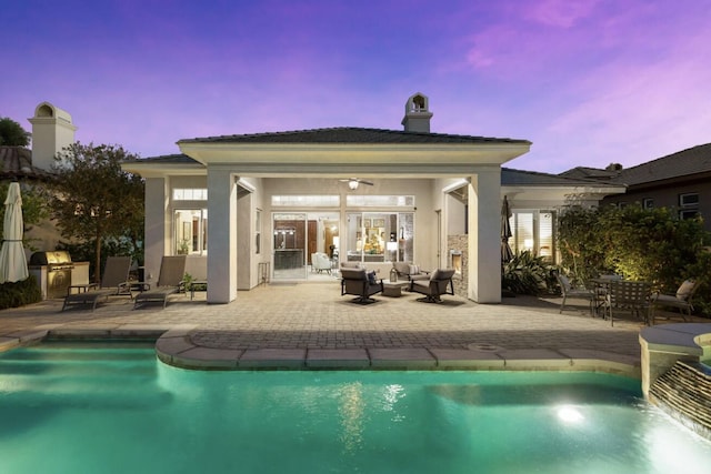 pool at dusk featuring an outdoor hangout area, a pool with connected hot tub, and a patio area