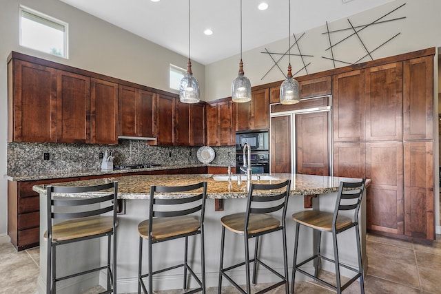 80220 Vía Tesoro, Tesoro, CA 92253 - kitchen with light stone countertops, a sink, an island with sink, decorative backsplash, and black appliances