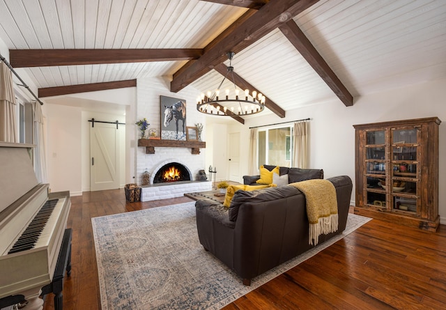 living area featuring a fireplace, a barn door, lofted ceiling with beams, wood-type flooring, and a chandelier
