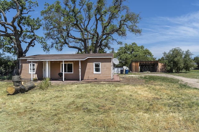 view of front facade featuring an outbuilding, a front lawn, and covered porch