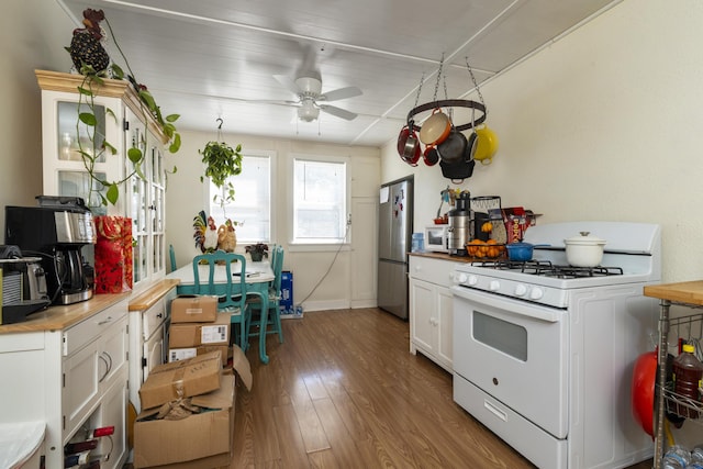 kitchen with wood finished floors, white appliances, baseboards, white cabinetry, and a ceiling fan
