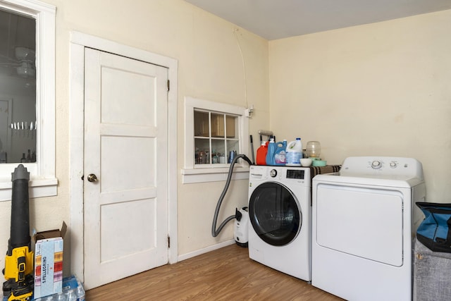 laundry area with baseboards, separate washer and dryer, laundry area, and wood finished floors