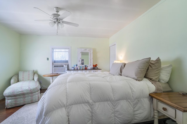 bedroom with a ceiling fan, wood finished floors, and cooling unit