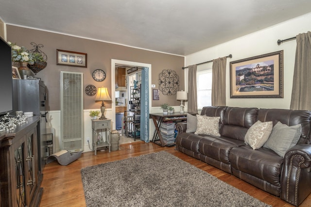 living area with crown molding, a heating unit, and wood finished floors