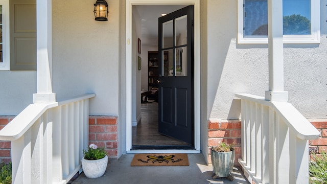 view of exterior entry with stucco siding and brick siding