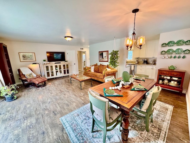 dining area featuring an inviting chandelier, wood finished floors, and visible vents