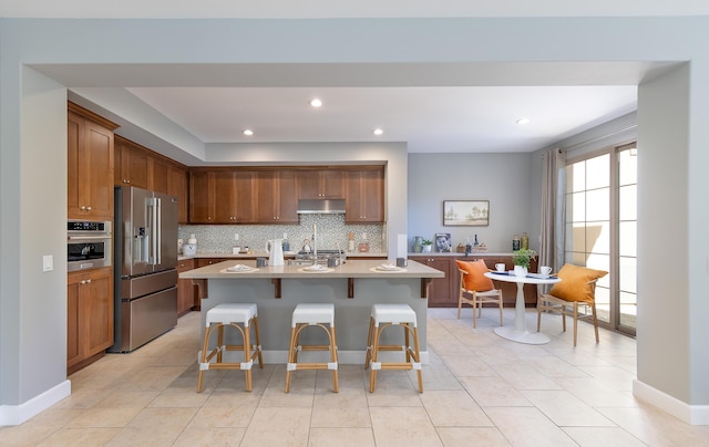 232 Sanderling Ln, Goleta, CA 93117 - kitchen featuring decorative backsplash, a breakfast bar area, light countertops, under cabinet range hood, and appliances with stainless steel finishes