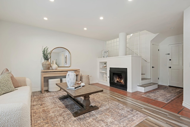 living room with wood finished floors, recessed lighting, a warm lit fireplace, and baseboards