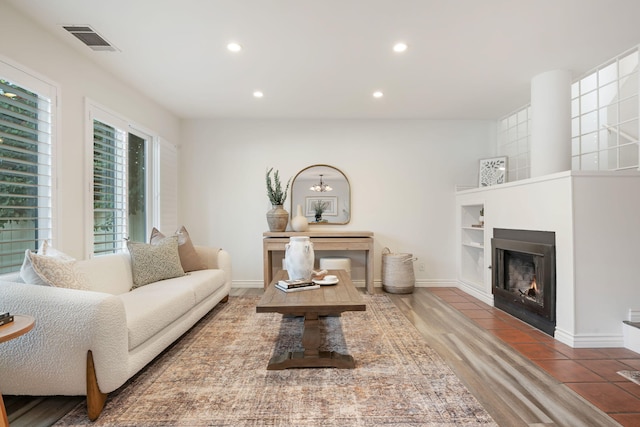 living room featuring recessed lighting, a lit fireplace, wood finished floors, and baseboards