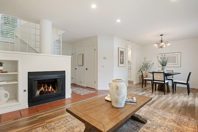living room featuring wood finished floors, a chandelier, a fireplace with flush hearth, recessed lighting, and built in features