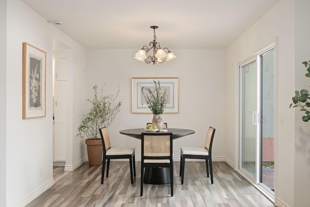 dining space featuring light wood-style floors, a chandelier, and baseboards