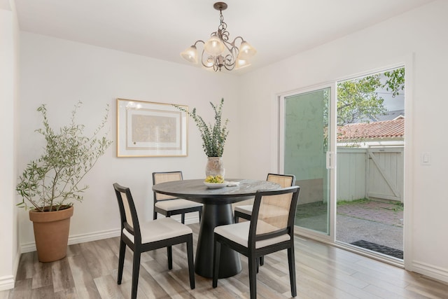dining area with light wood finished floors, a chandelier, and baseboards