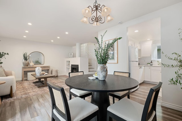 dining area with light wood-style flooring, recessed lighting, stairway, a chandelier, and baseboards